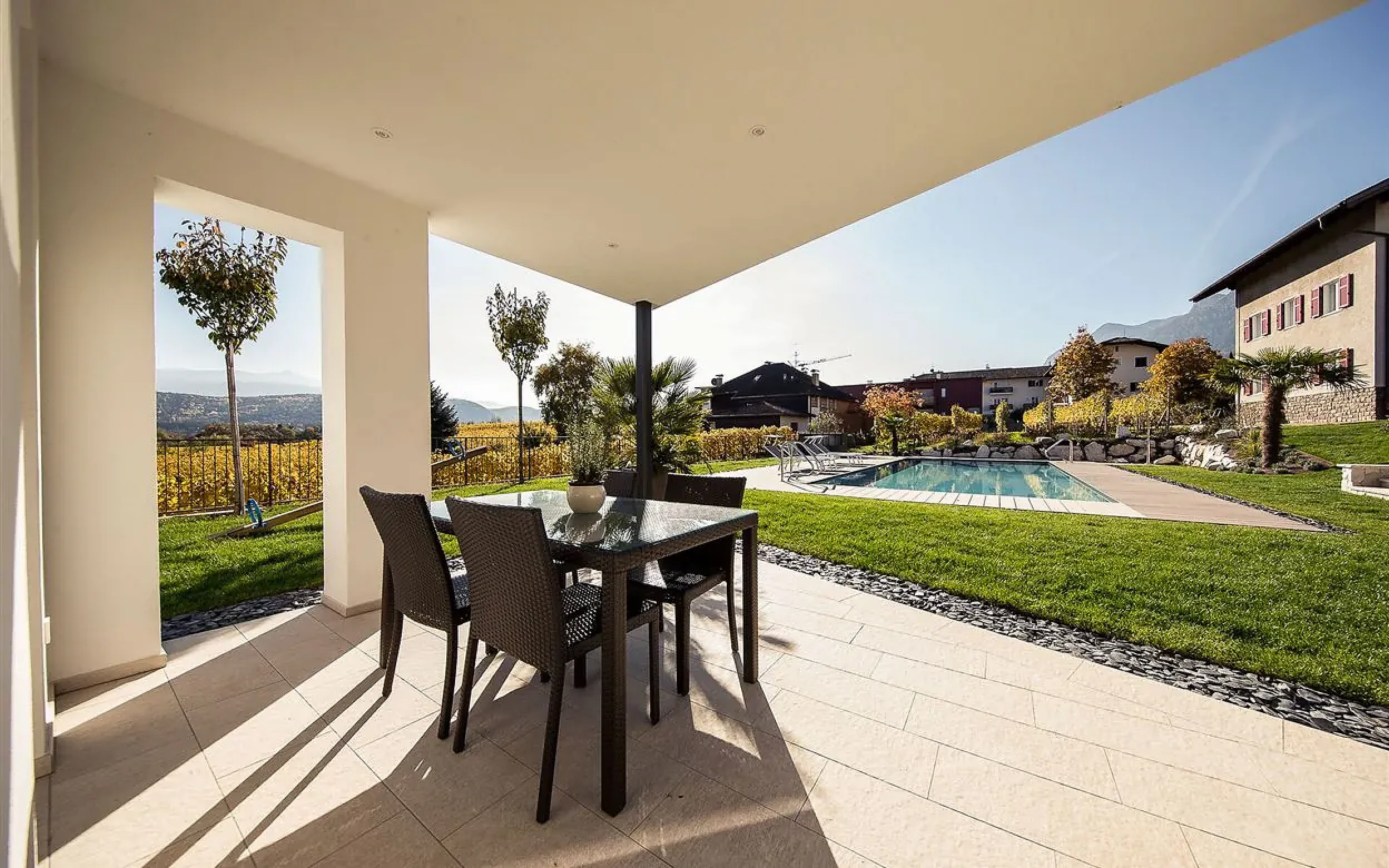 Überdachte Terrasse mit Blick auf Pool und Garten